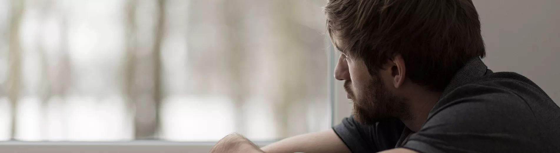 A man looks out a window at a depression treatment center.